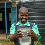 Student holding container of clean water thanks to Dig Deep