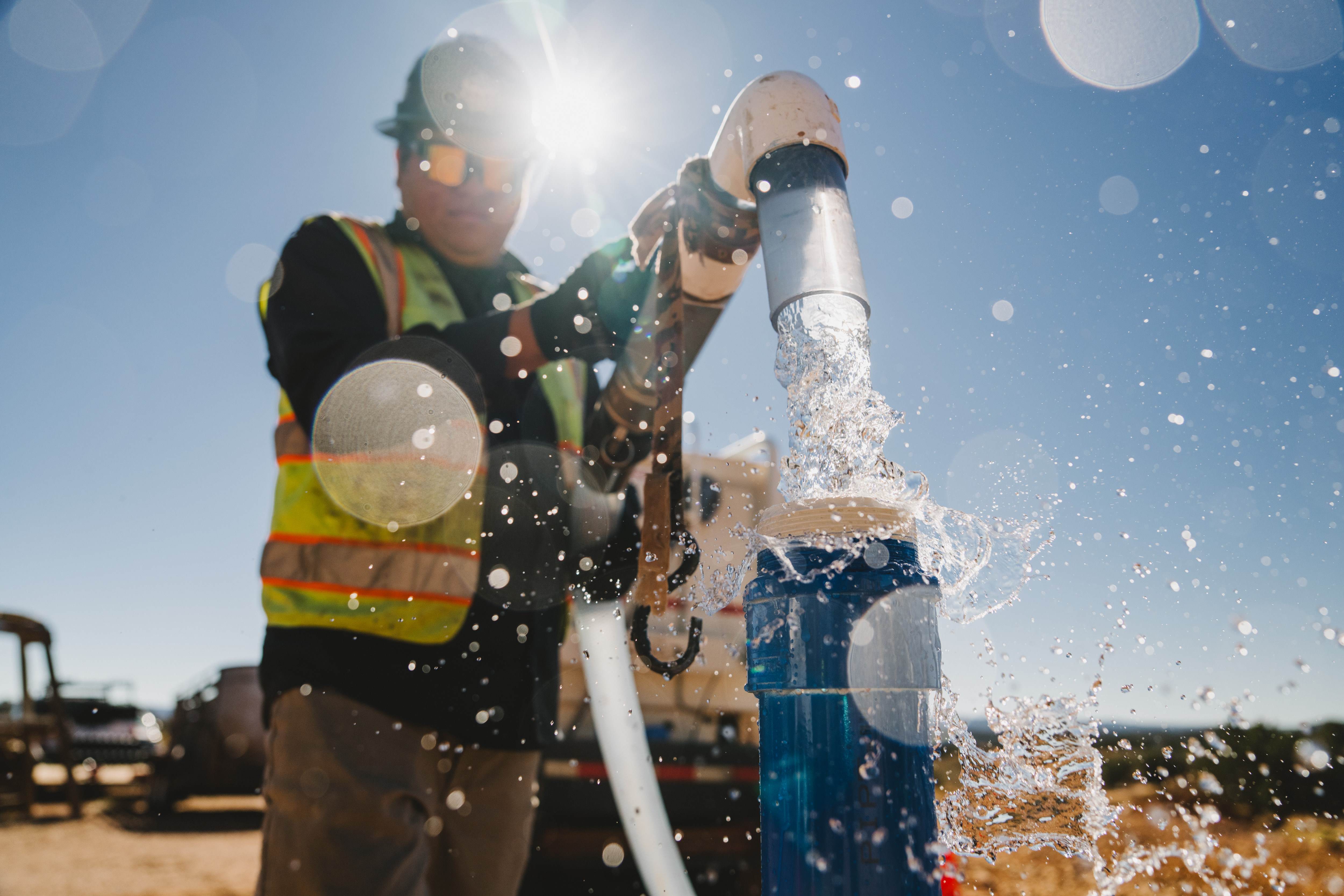 Workman in safety wear working with running water